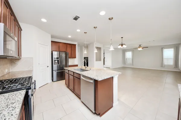 a kitchen with stainless steel appliances granite countertop a kitchen island a stove a sink and a microwave