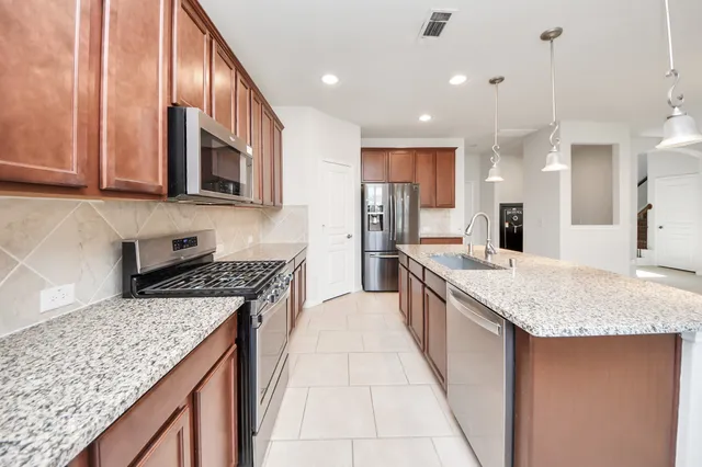 a kitchen with granite countertop kitchen island a sink appliances and a counter space