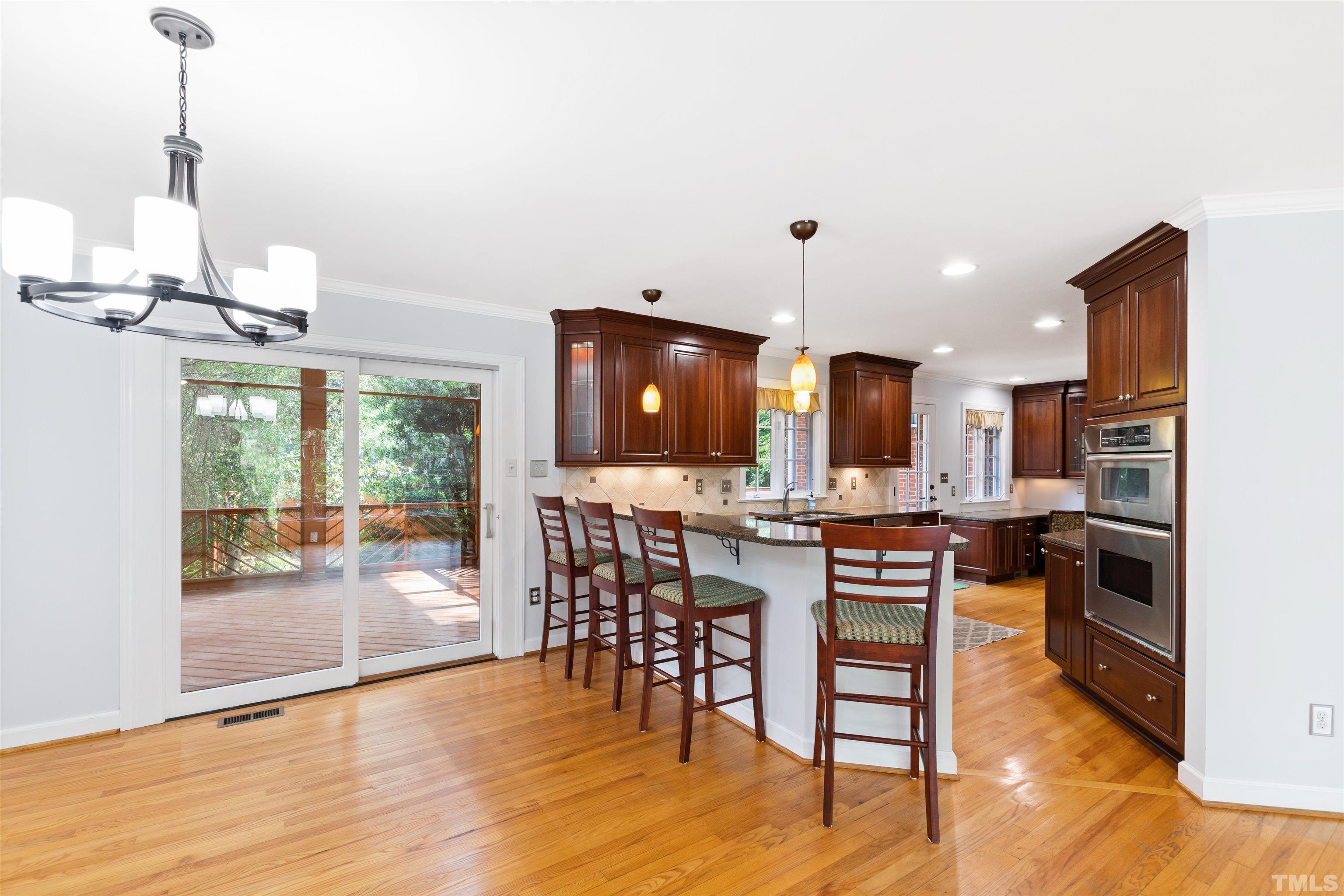 1320 Diehl Street Raleigh, NC 27608 - Photo 10 of 47 a open kitchen with stainless steel appliances granite countertop a stove top oven a sink a dining table and chairs with wooden floor