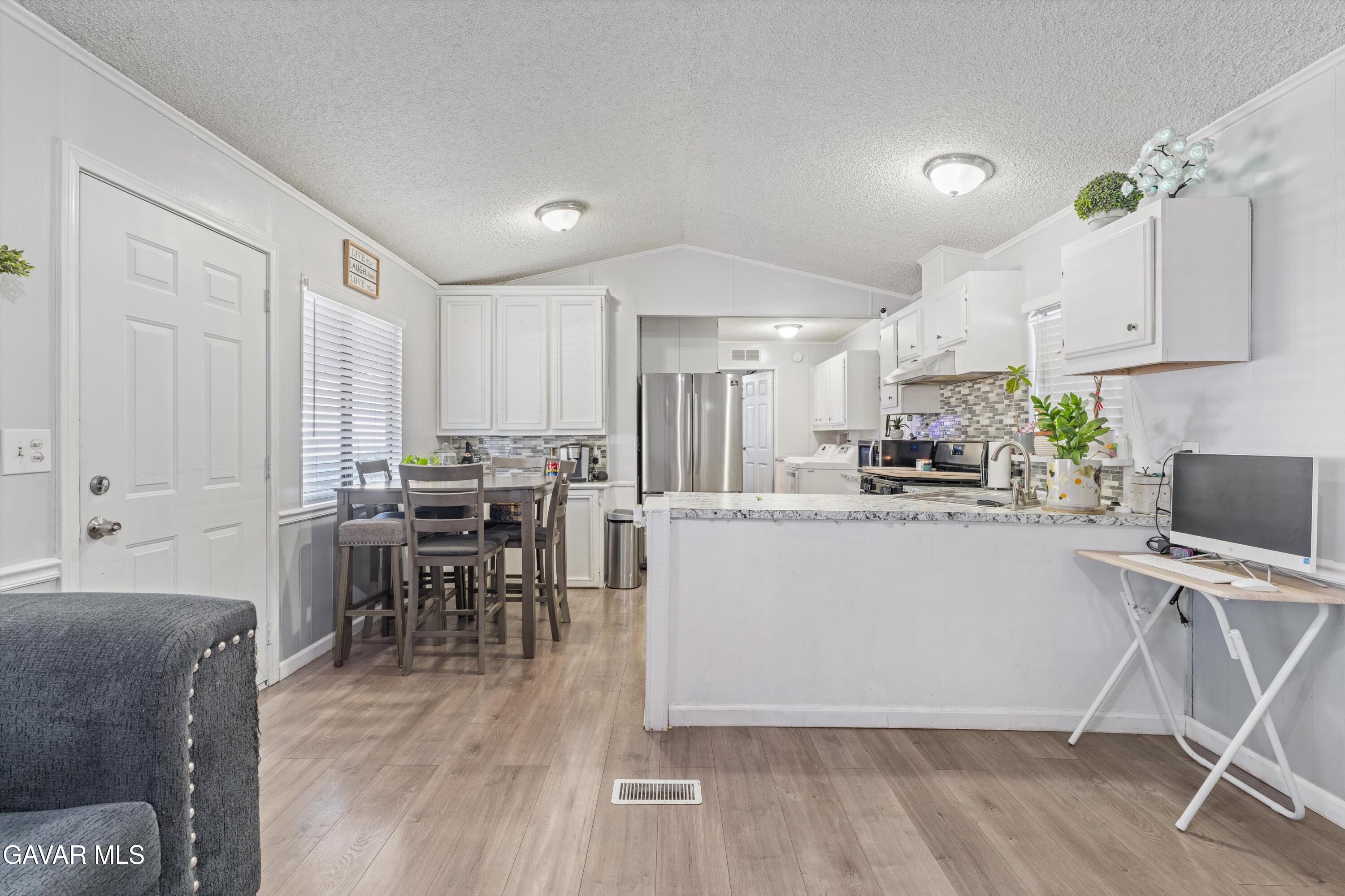 5711 Columbia Way Lancaster, CA 93536 - Photo 19 of 21 a kitchen with a table chairs refrigerator and cabinets