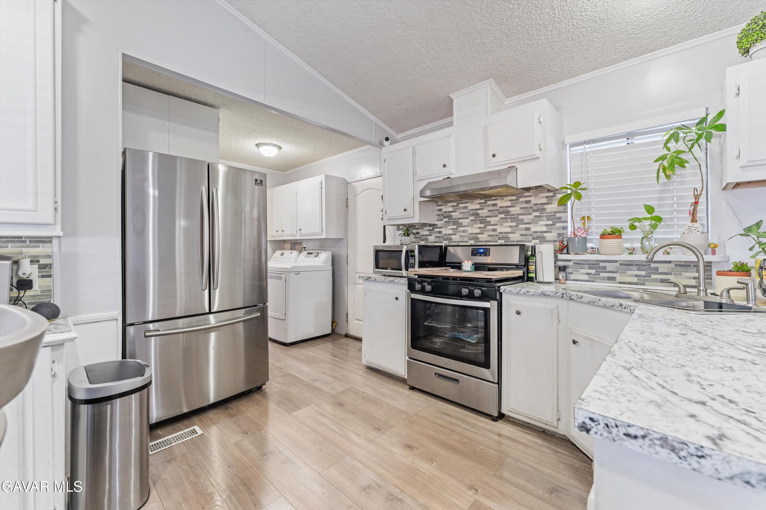 5711 Columbia Way Lancaster, CA 93536 - Photo 20 of 21 a kitchen with a refrigerator stove and white cabinets