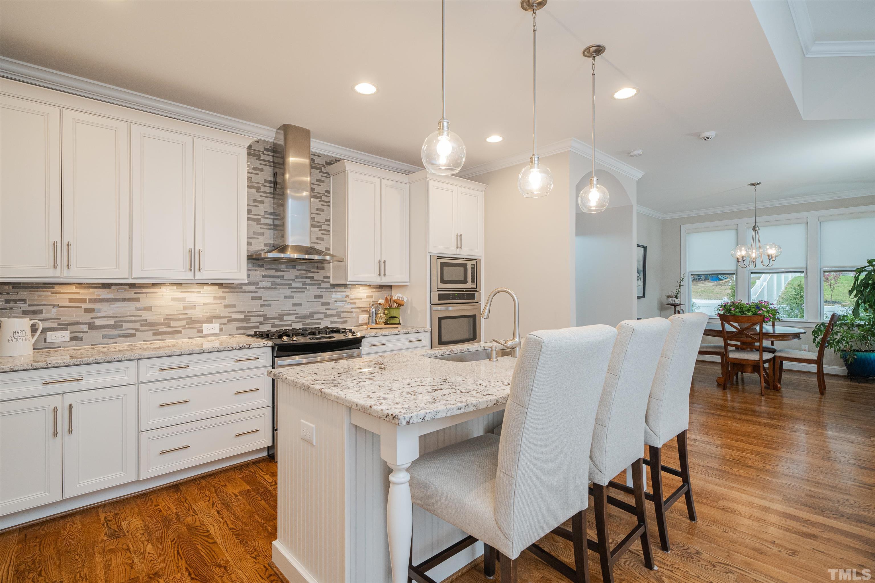 616 Connington Way Rolesville, NC 27571 - Photo 24 of 51 a kitchen with stainless steel appliances granite countertop a stove top oven a sink dishwasher a dining table and chairs with wooden floor