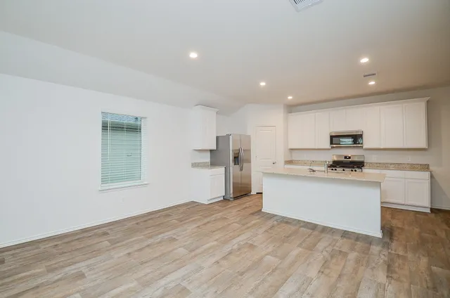 a kitchen with stainless steel appliances granite countertop a stove top oven a sink and a refrigerator