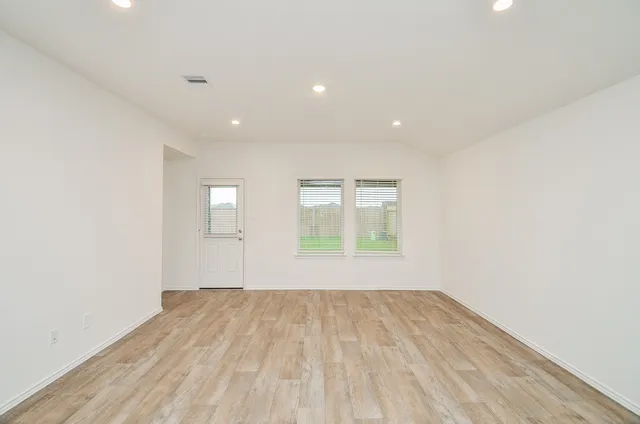 an empty room with wooden floor and windows