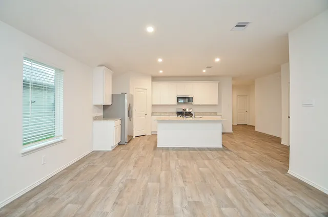 a large kitchen with kitchen island white cabinets and stainless steel appliances
