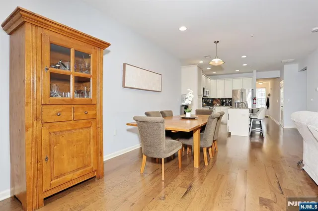 a dining room with stainless steel appliances kitchen island granite countertop a table chairs and a wooden floor