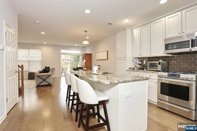 a kitchen with stainless steel appliances granite countertop a stove a sink a oven a dining table and chairs