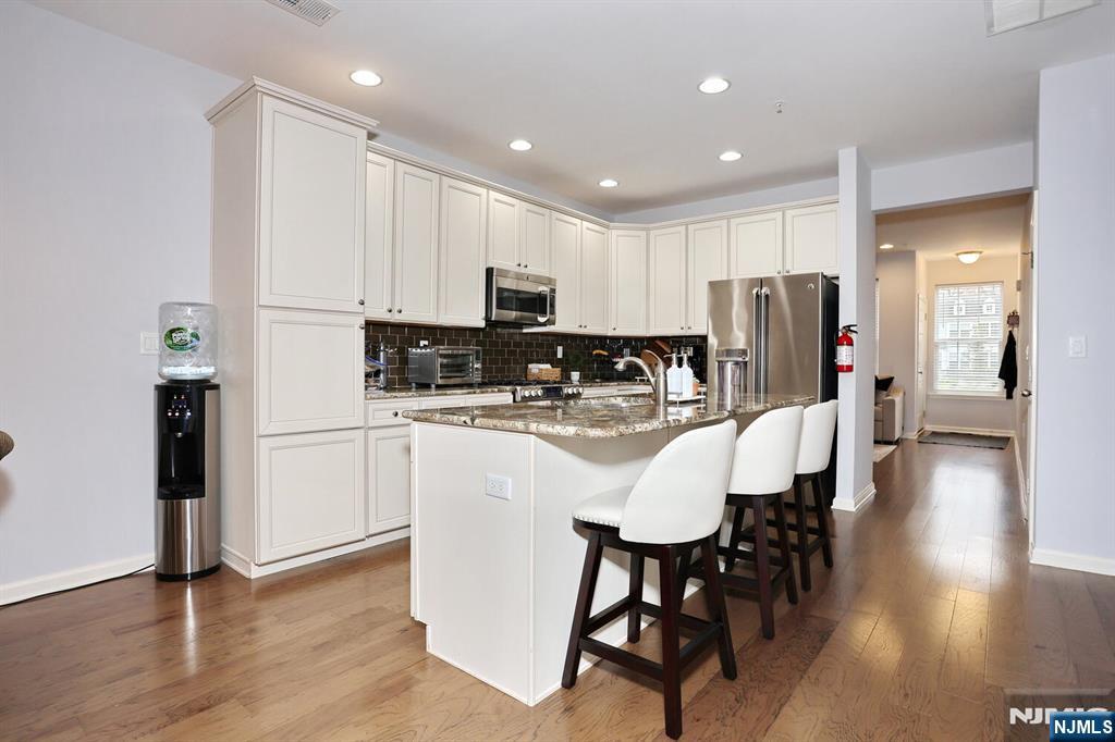 4 Masterson Court, Unit 4 Waldwick, NJ 07463 - Photo 8 of 26 a kitchen with stainless steel appliances granite countertop a refrigerator a stove a sink a dining table and chairs with wooden floor