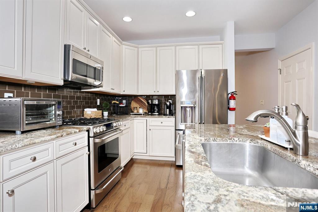 4 Masterson Court, Unit 4 Waldwick, NJ 07463 - Photo 9 of 26 a kitchen with stainless steel appliances granite countertop a sink stove and refrigerator
