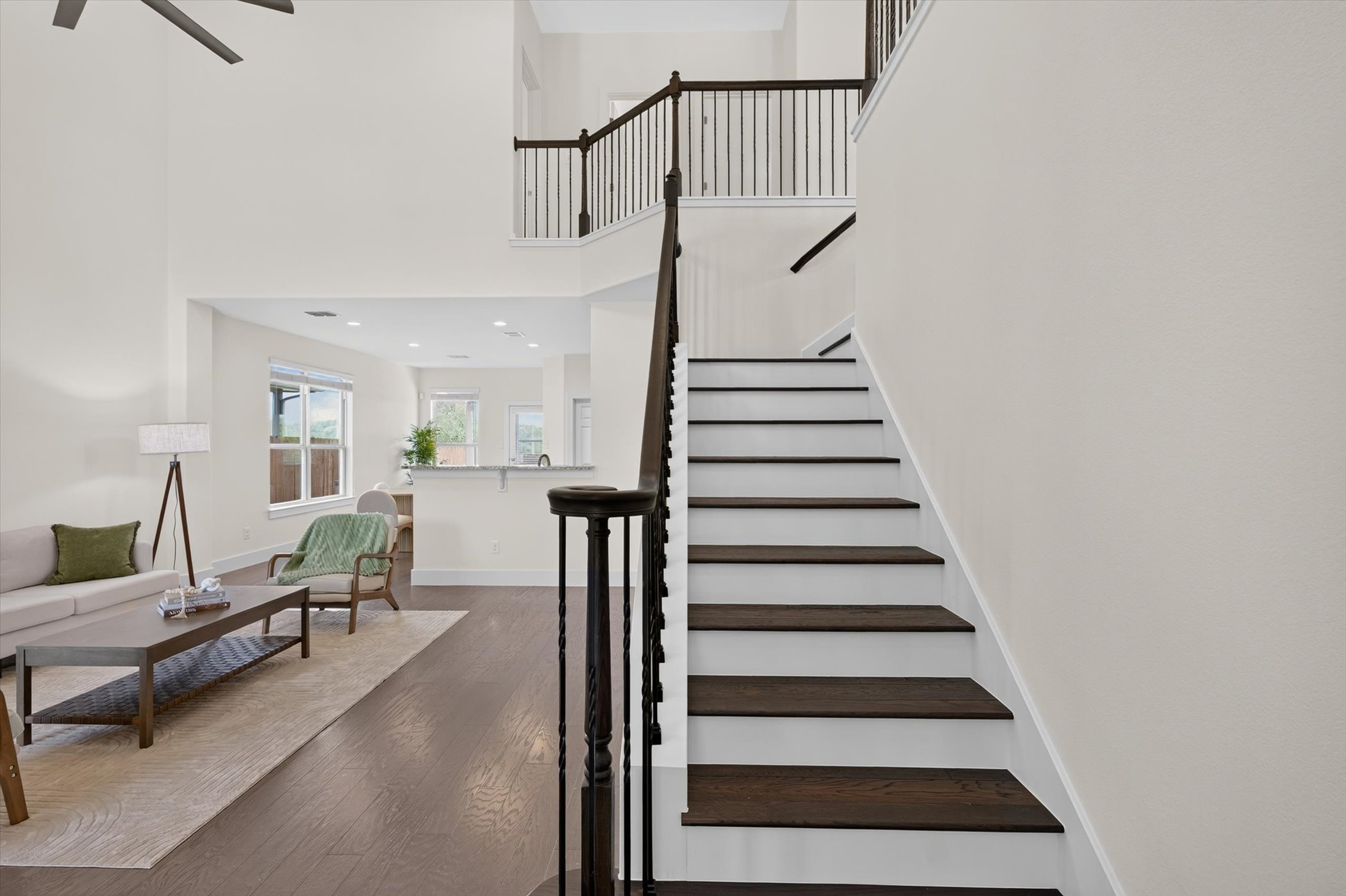 An open entryway connects the living space and stairs under towering ceilings.