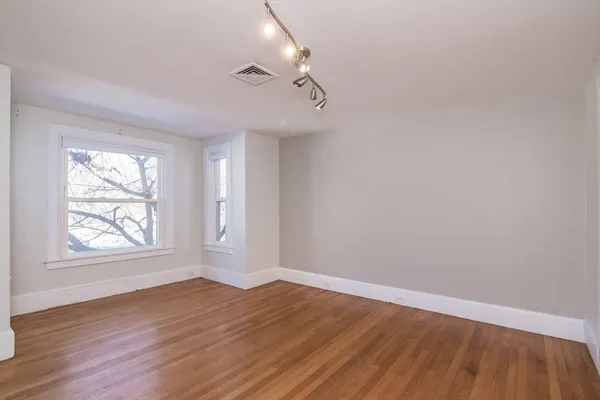 an empty room with wooden floor and windows
