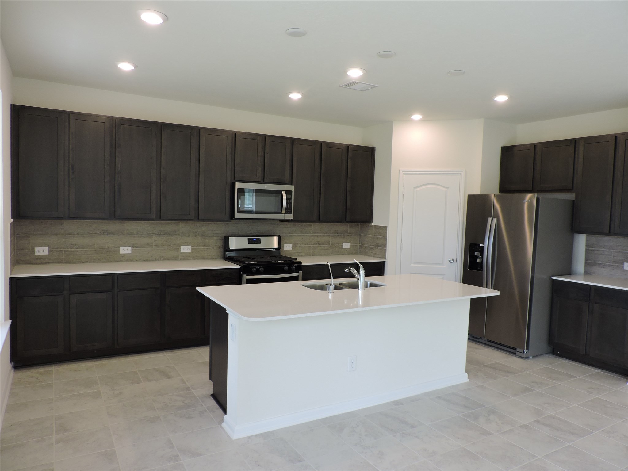 1122 Epworth Ct. Conroe, TX 77304 - Photo 8 of 35 a kitchen with kitchen island a cabinets and refrigerator