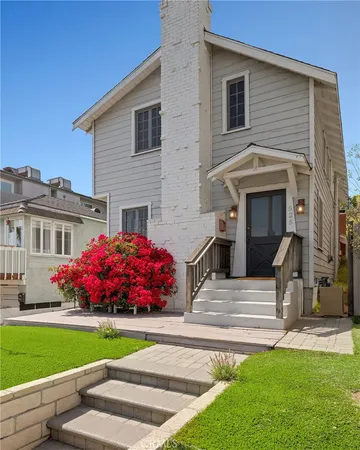 a front view of house and yard with beautiful flowers and wooden fence