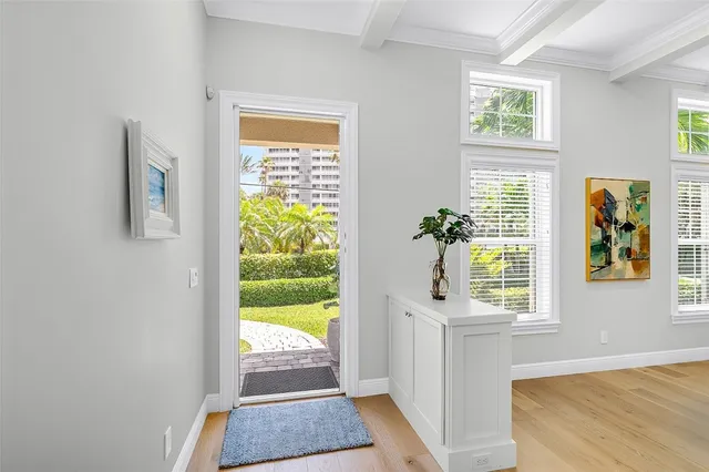 a view of an entryway with wooden floor leading to a furnished livingroom and windows