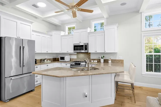 a kitchen with stainless steel appliances granite countertop a refrigerator a stove oven a sink dishwasher and white cabinets with wooden floor