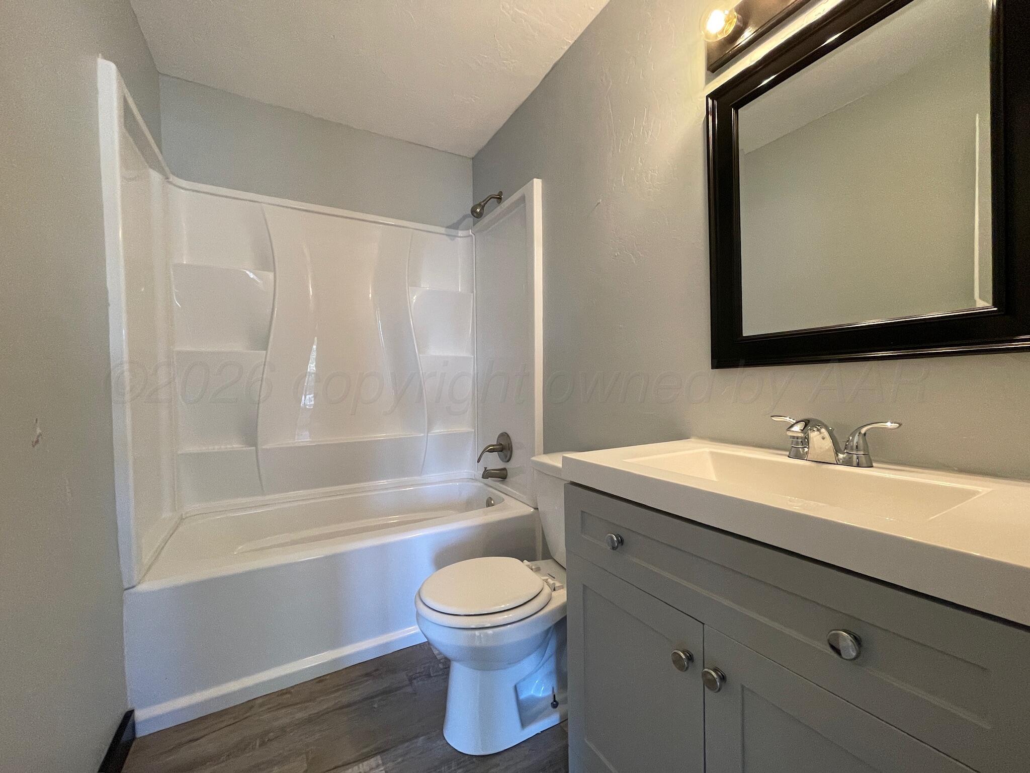 4630 South Ong Street Amarillo, TX 79110 - Photo 6 of 7 a bathroom with a toilet a sink a mirror a bathtub and vanity
