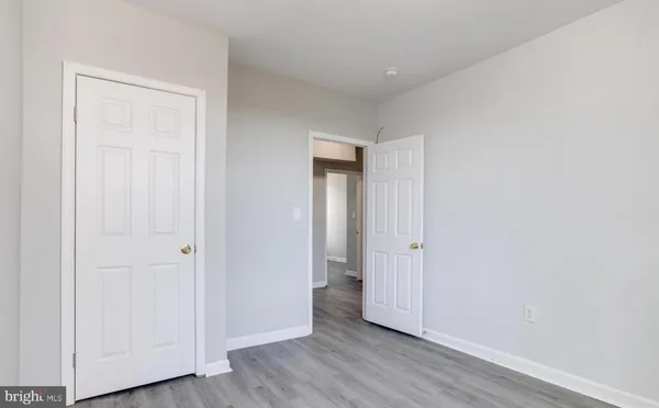 an empty room with wooden floor & closet area