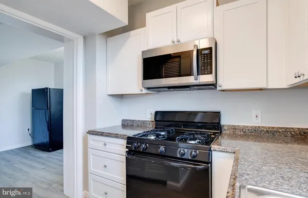 a kitchen with stainless steel appliances granite countertop white cabinets and a stove top oven