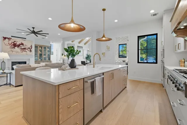 a kitchen with stainless steel appliances granite countertop a sink a stove and a wooden floors