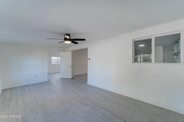 an empty room with wooden floor fan and windows