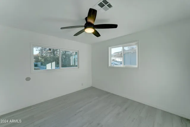 a view of empty room with wooden floor and ceiling fan
