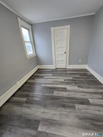 a view of an empty room with wooden floor and window