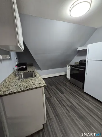 a kitchen with granite countertop a sink a stove and cabinets