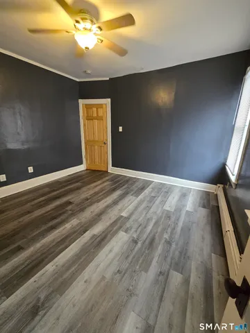 a view of an empty room with window and wooden floor