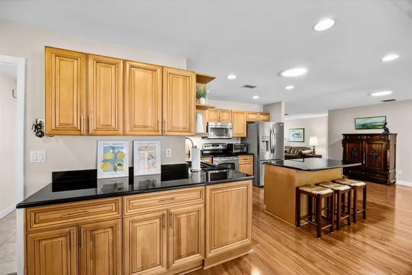 a kitchen with stainless steel appliances granite countertop a stove top oven a sink dishwasher a dining table and chairs with wooden floor