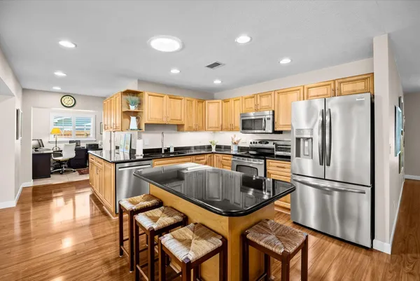 a kitchen with granite countertop stainless steel appliances a refrigerator a stove a sink a dining table and chairs