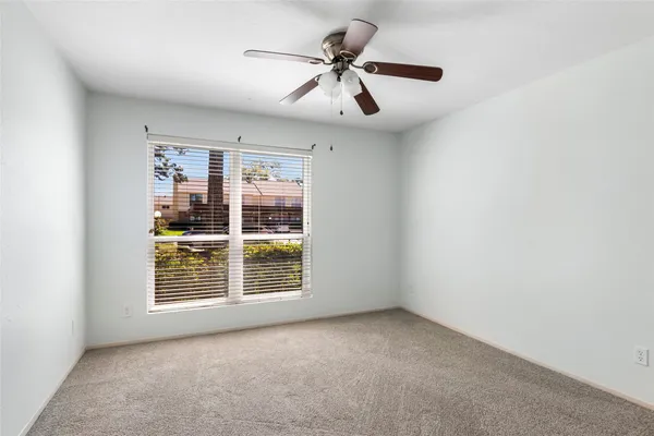 an empty room with windows and ceiling fan
