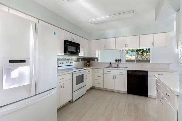 a kitchen with granite countertop white cabinets and white appliances