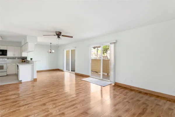 a view of empty room with wooden floor and kitchen view