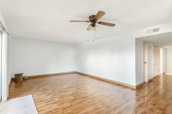 a view of a room with wooden floor and a ceiling fan