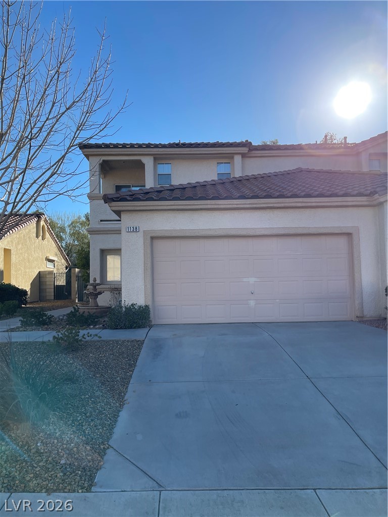 View of front facade with an attached garage, concrete driveway, stucco siding, and a tile roof