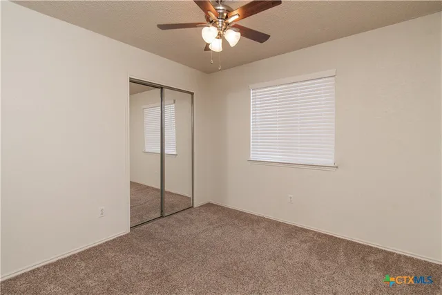 an empty room with closet and a chandelier fan