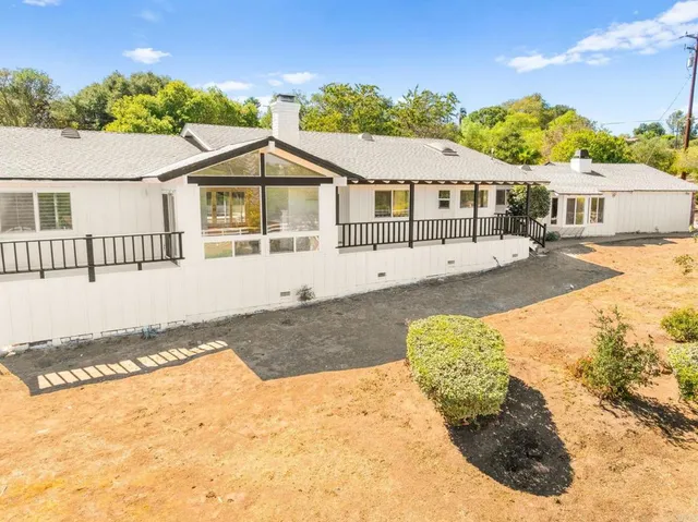 a view of a livingroom with a fireplace a ceiling fan and windows