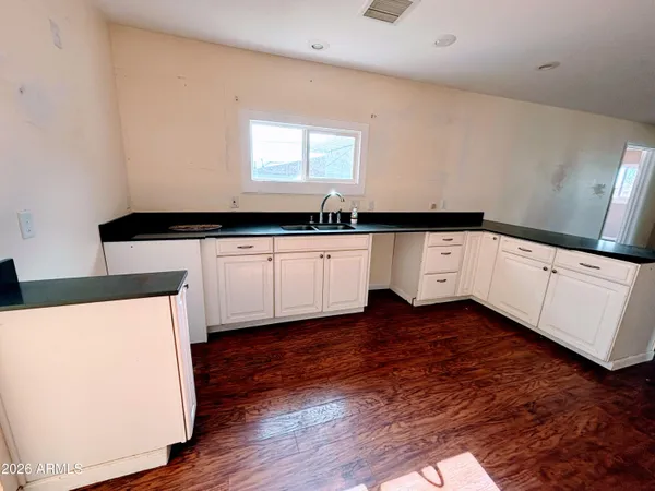 a kitchen with stainless steel appliances a sink a stove a microwave a sink and white cabinets