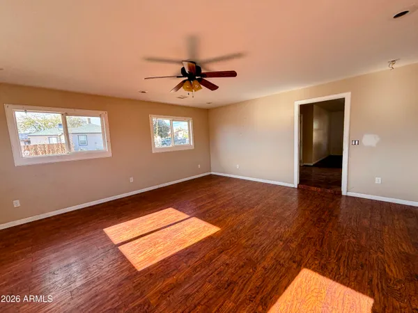 a view of empty room with wooden floor and fan