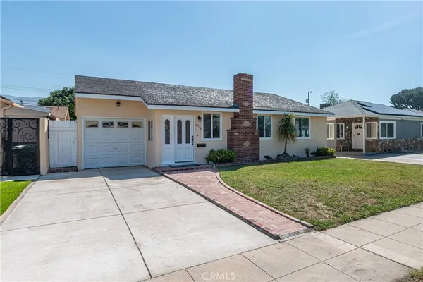 a front view of a house with a yard and potted plants