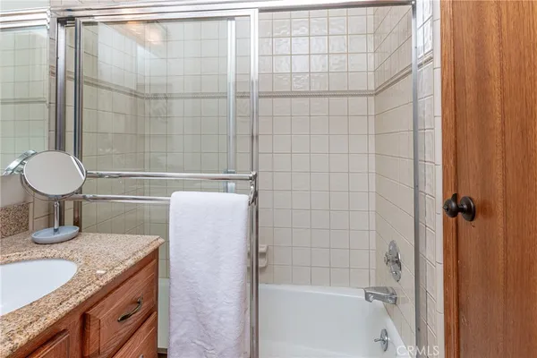 a bathroom with a granite countertop bathtub shower sink vanity and toilet