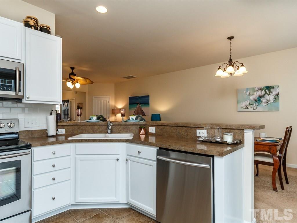 8321 Pilots View Drive Raleigh, NC 27617 - Photo 13 of 25 a kitchen with a sink dishwasher and white cabinets with wooden floor