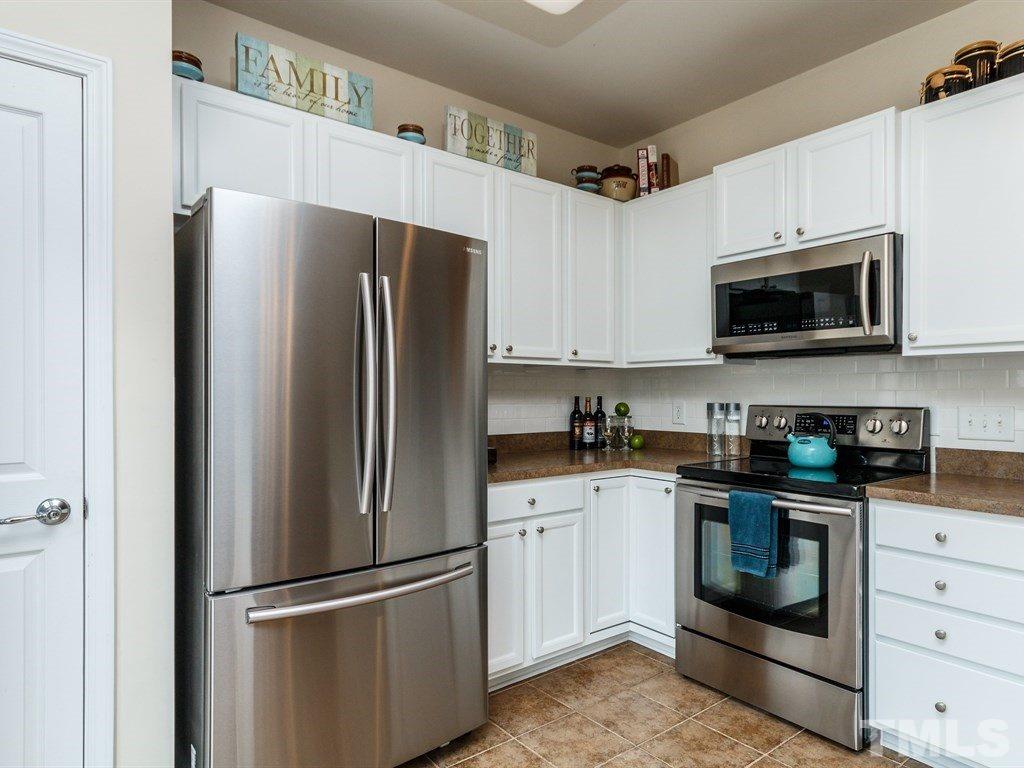 8321 Pilots View Drive Raleigh, NC 27617 - Photo 14 of 25 a kitchen with stainless steel appliances granite countertop a refrigerator stove a sink and dishwasher with wooden cabinet