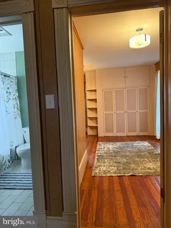 a view of an empty room with wooden floor and a bathroom