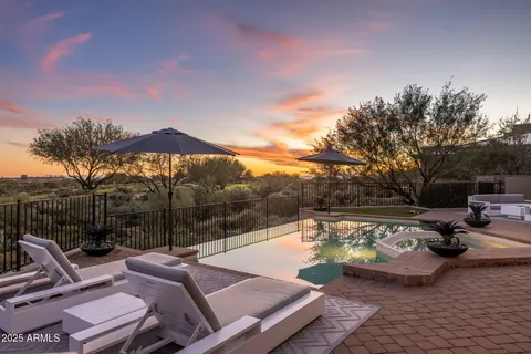 a view of swimming pool with seating area and trees in the background