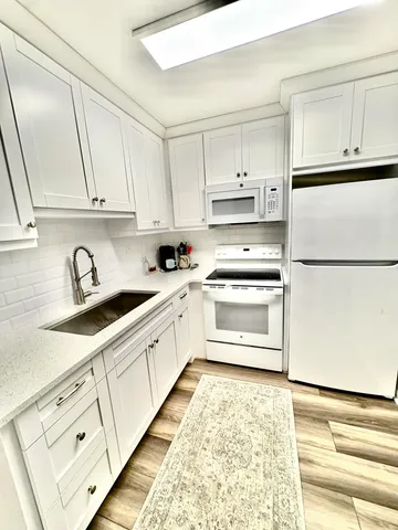 a kitchen with granite countertop white cabinets and white appliances