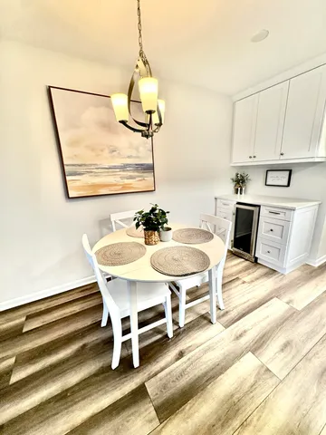 a dining room with wooden floor a chandelier a wooden table and chairs