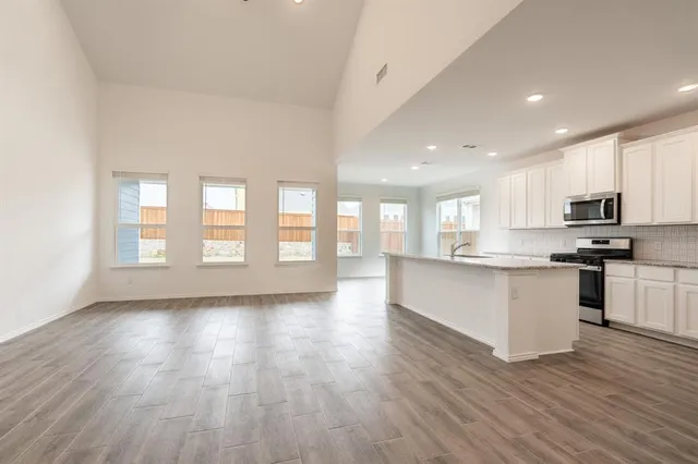 a large kitchen with stainless steel appliances granite countertop a large counter top and a wooden floors