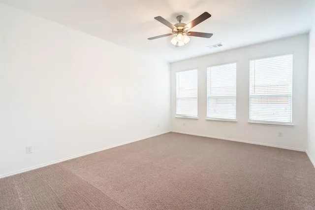 an empty room with windows and ceiling fan