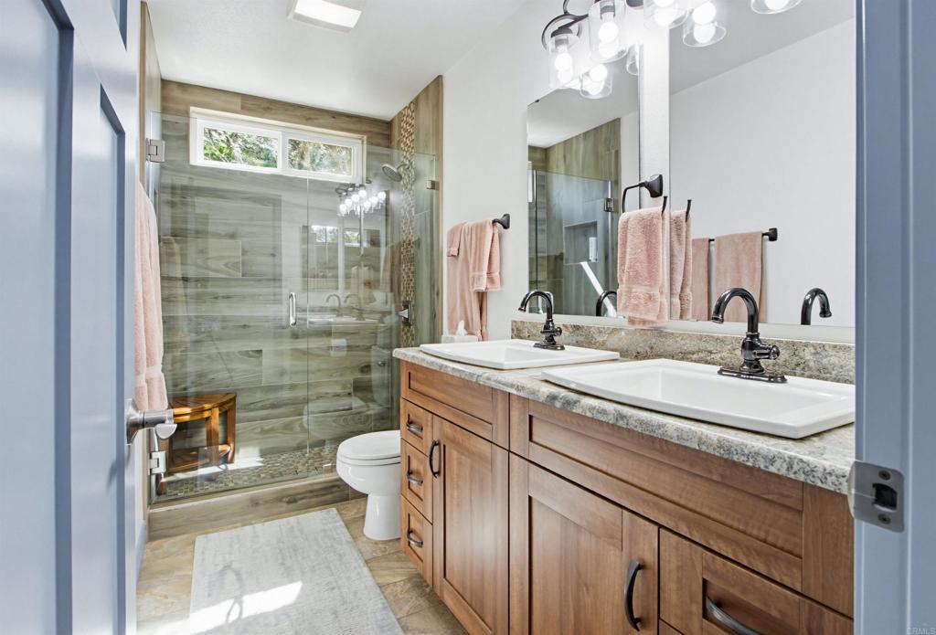2194 Stone Castle Fallbrook, CA 92028 - Photo 38 of 60 a bathroom with a granite countertop sink a toilet a mirror and shower